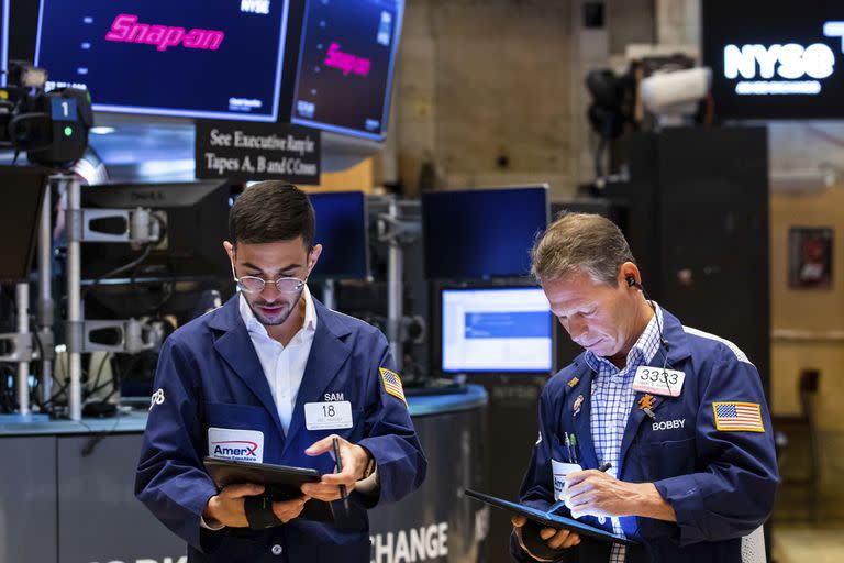 En esta fotografía proporcionada por la Bolsa de Valores de Nueva York, los corredores Orel Partush (izquierda) y Robert Charmak trabajan. (David L. Nemec/New York Stock Exchange via AP)