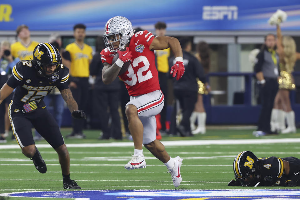 Ohio State running back TreVeyon Henderson (32) runs between Missouri defensive back Dreyden Norwood (12) and defensive back Tre'Vez Johnson (4) during the first half of the Cotton Bowl NCAA college football game Friday, Dec. 29, 2023, in Arlington, Texas. (AP Photo/Richard W. Rodriguez)