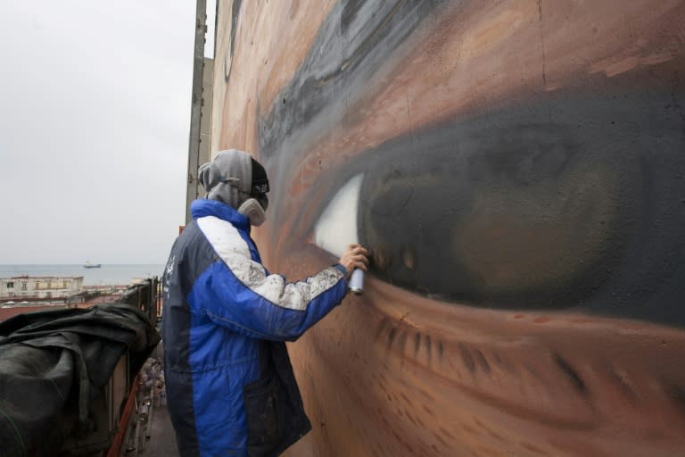 Italian artist Jorit Agoch works on a mural representing football superstar Diego Armando Maradona