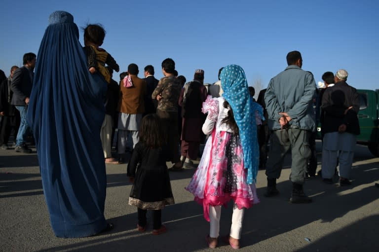 An Afghan woman and children near the gate of Ministry of Defence in Kabul on February 27, 2016 as security personnel cordon off the scene of a suicide bombing