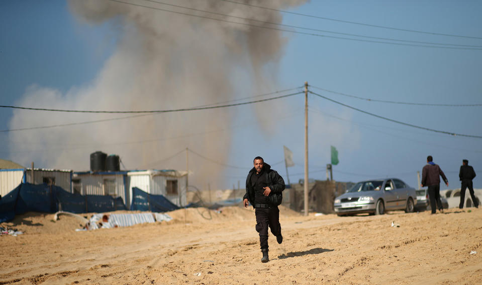 Palestinian security officer runs as smoke rises following Israeli air strike