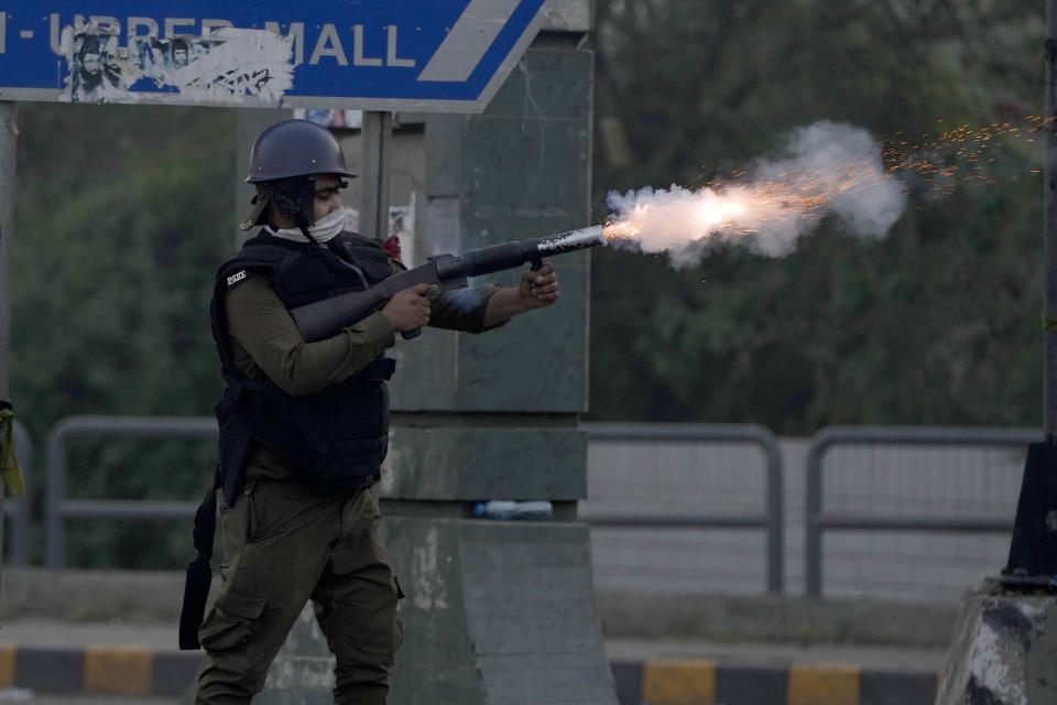 A riot police officer fires tear gas to disperse supporters of former Prime Minister Imran Khan during clashes, in Lahore, Pakistan, Wednesday, March 15, 2023. Clashes between Pakistan's police and supporters of Khan persisted outside his home in the eastern city of Lahore on Wednesday, a day after officers went to arrest him for failing to appear in court on graft charges. (AP Photo/K.M. Chaudary)