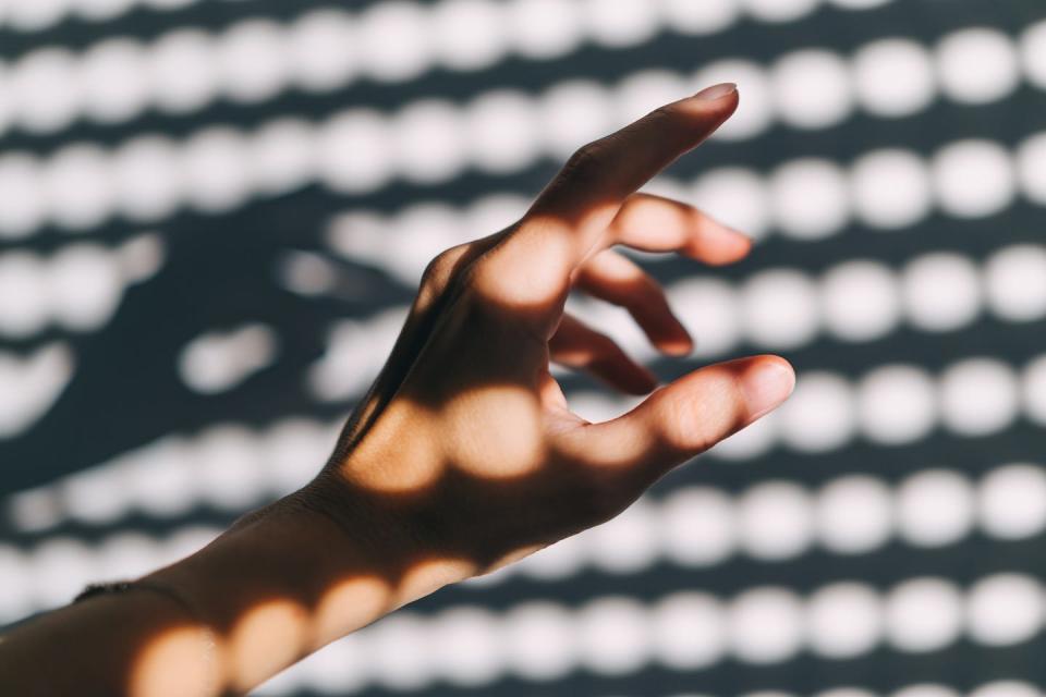 female hand in sunny day, wall with light circles in a background