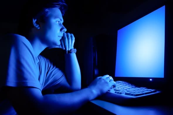 Man in front of computer screen. Dark night room and blue light.