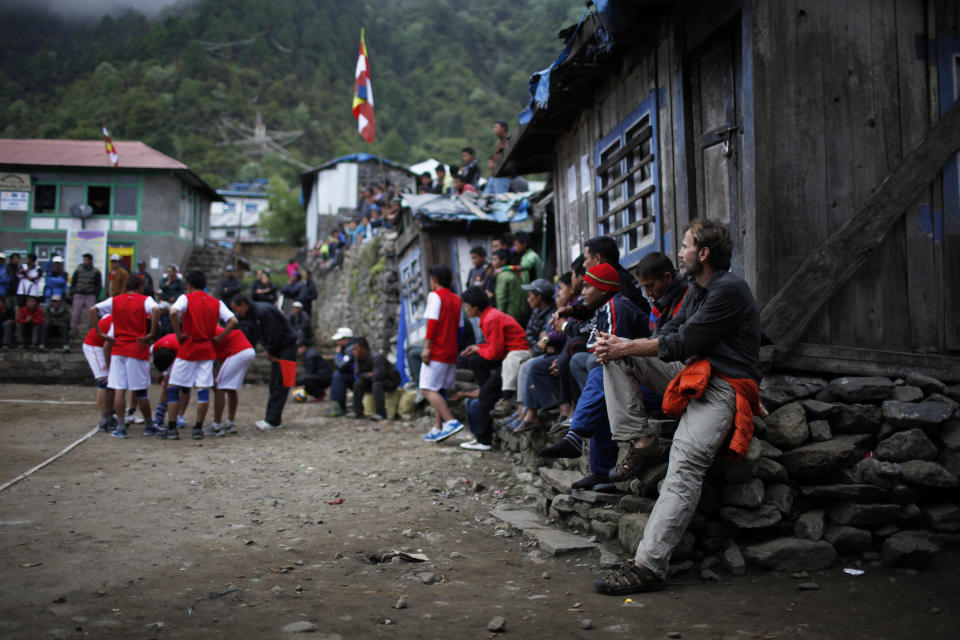 In this Saturday, May 25, 2013 photo, a passenger, right, watches a volleyball match as he waits for flight services to resume at Lukla airport, Nepal. Carved out of side of a mountain, the airport was built by Sir Edmund Hillary in 1965, and at an altitude of 2,843 meters (9,325 feet) it has earned the reputation of being one of the most extreme and dangerous airports in the world. (AP Photo/Niranjan Shrestha)