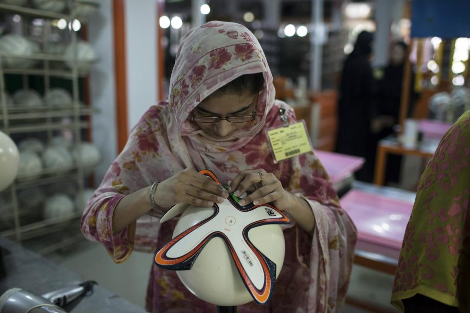 An employee adjusts outer panels of a soccer ball inside the soccer ball factory that produces official match balls for the 2014 World Cup in Brazil, in Sialkot, Punjab province