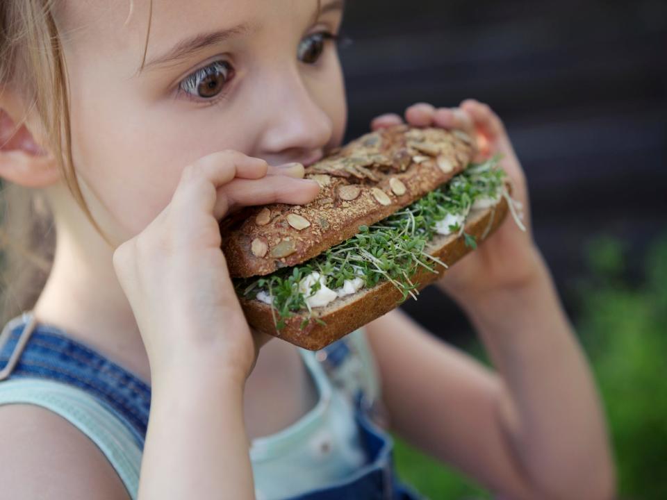 Girl taking a bite out of a sandwich.