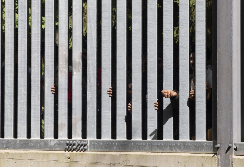 Members of a group of some 30 migrants seeking asylum are seen in Bialowieza, Poland, on Sunday, 28 May 2023 across a wall that Poland has built on its border with Belarus to stop massive migrant pressure. The group has remained stuck at the spot for three days, according to human rights activists. (AP Photo/Agnieszka Sadowska)