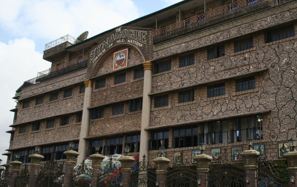 FILE - This Sunday, Sept. 15, 2013 file photo shows the exterior of The Synagogue, Church Of All Nations in Lagos Nigeria. T.B. Joshua's Synagogue, Church of All Nations has branches around the world, and a recent YouTube video even credits him with predicting the disappearance of Malaysian Airlines Flight MH370. Joshua is one of the best-known preachers in Africa and among the most profitable in Nigeria, the go-to faith healer and spiritual guide for leaders such as the late Ghanaian president John Atta Mills, Malawian president Joyce Banda and former Zimbabwean prime minister Morgan Tsvangirai. The man who says he comes from the poor village of Arigidi is worth between $10 and $15 million based on assets, according to Forbes magazine, which in 2011 estimated his personal wealth. The church holds some 15,000 people with outside tents for the overflow and Sunday services are beamed worldwide. Yet critics say this wildly popular televangelist hinders efforts to curtail the spread of HIV and tuberculosis with testimonies by church-goers that faith and his holy water can cure both. He is also accused of taking advantage of his followers and tightly controlling those closest to him, who call him "Daddy."(AP Photo/Carley Petesch, file)