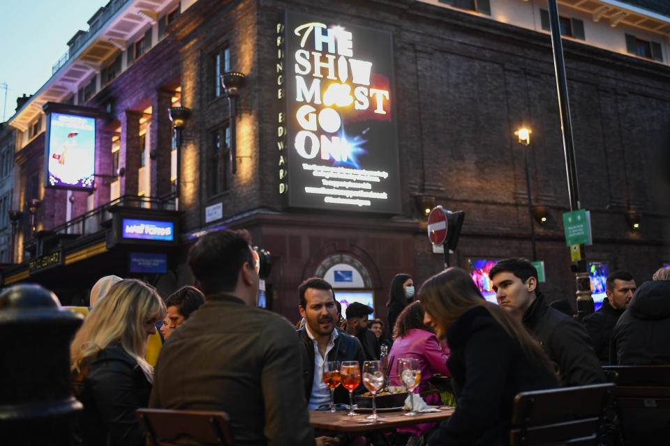 People sit at setup tables outside a pub in Soho, in London, on the day some of England's third coronavirus lockdown restrictions were eased by the British government, Monday, April 12, 2021. People across England flocked to shed shaggy locks and browse for clothes, books and other "non-essential" items as shops, gyms, hairdressers, restaurant patios and beer gardens reopened Monday after months of lockdown. (AP Photo/Alberto Pezzali)