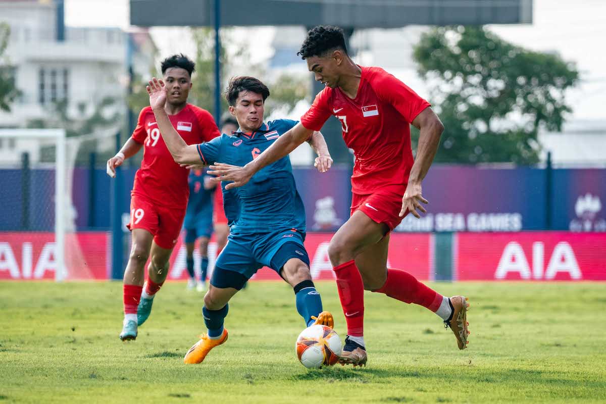 Singapore forward Jordan Emaviwe (right) battles for the ball with Thailand's Airdan Doloh during their Group B clash at the 2023 SEA Games. (PHOTO: SNOC/Eng Chin An)