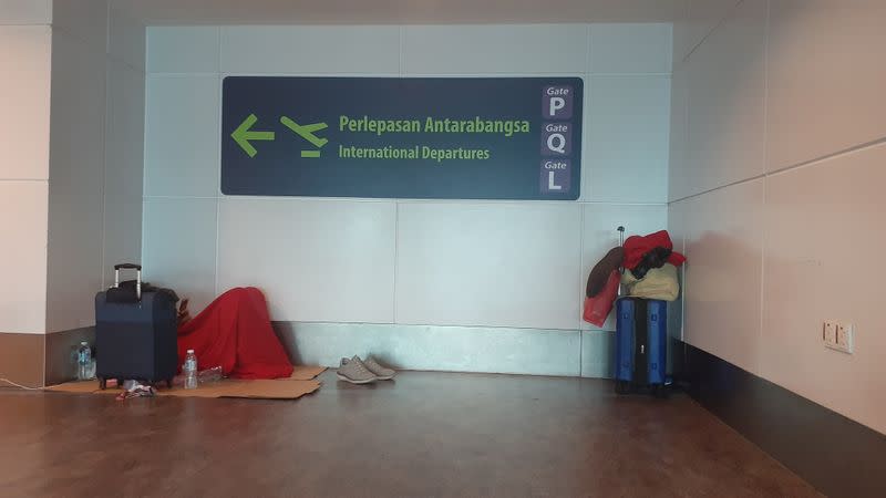 Stranded tourists sit in chairs at the transit area of Kuala Lumpur International Airport in Sepang