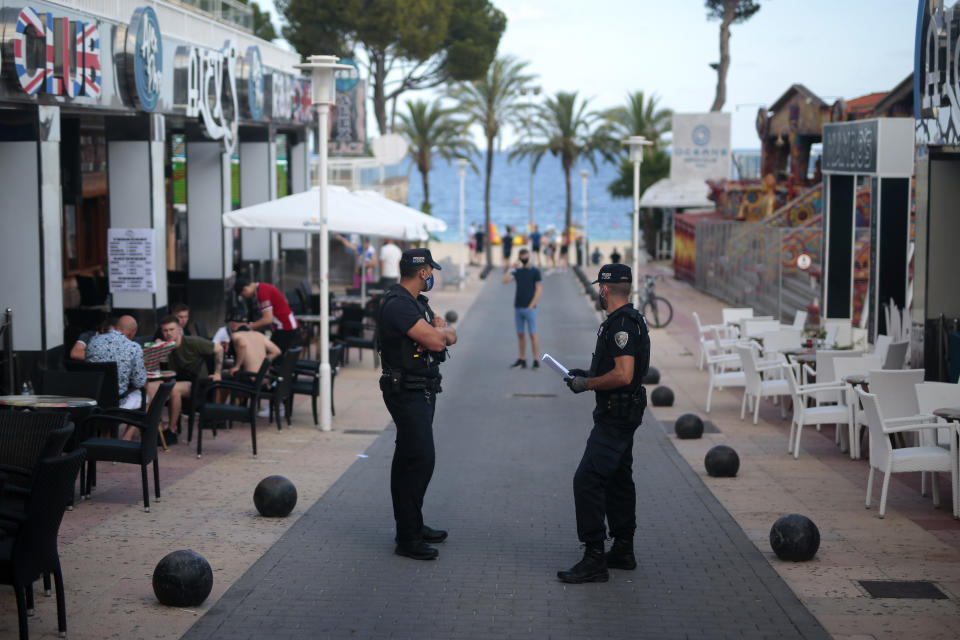 Police officers patrol at the resort of Magaluf on the Spanish Balearic island of Mallorca, Spain, Thursday, July 16, 2020. In a move designed to stop the spread of the new coronavirus and shake off the region's reputation as a party hub, regional authorities in the Balearic Islands ordered the closure from Thursday of all establishments along Mallorca's "Beer St." and "Ham St.", as the popular party areas near the beach of Palma de Mallorca are known, and another boulevard in nearby Magaluf. (AP Photo/Joan Mateu)