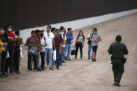 A Border Patrol agent instructs migrants who had crossed the Rio Grande river into the United States in Eagle Pass, Texas, Friday, May 20, 2022. The Eagle Pass area has become increasingly a popular crossing corridor for migrants, especially those from outside Mexico and Central America, under Title 42 authority, which expels migrants without a chance to seek asylum on grounds of preventing the spread of COVID-19. A judge was expected to rule on a bid by Louisiana and 23 other states to keep Title 42 in effect before the Biden administration was to end it Monday. (AP Photo/Dario Lopez-Mills)