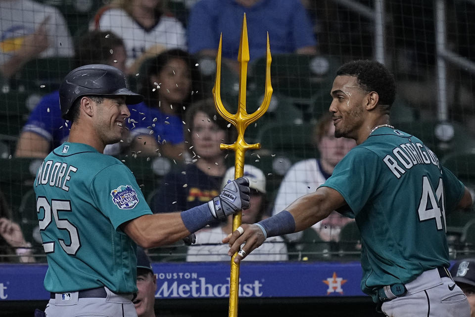 Seattle Mariners' Dylan Moore (25) is presented with a trident by Julio Rodriguez after hitting a solo home run during the ninth inning of a baseball game against the Houston Astros, Saturday, Aug. 19, 2023, in Houston. (AP Photo/Kevin M. Cox)