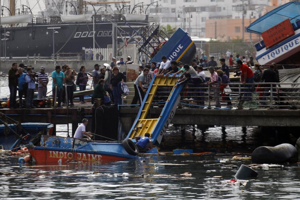 Pescadores intentan rescatar los restos de un bote destruido durante un terremoto en el puerto de Iquique, en Chile, el miércoles 2 de abril de 2014. La suspensión el miércoles de la alerta de tsunami que afectó las costas chilenas tras el terremoto de magnitud 8,2 ocurrido en el extremo norte del país, permitió el lento regreso a sus hogares de decenas de miles de personas que amanecieron al aire libre. (AP foto/ Luis Hidalgo, Pool)