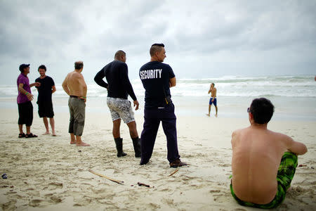 Tourists and a security agent are seen on a beach a day after the passage of Hurricane Irma in Varadero, Cuba, September 10, 2017. REUTERS/Alexandre Meneghini