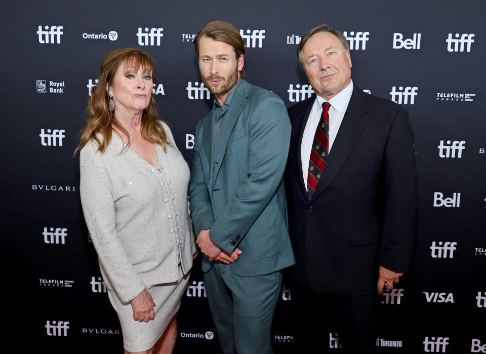 glen powell posing with his parents on the red carpet