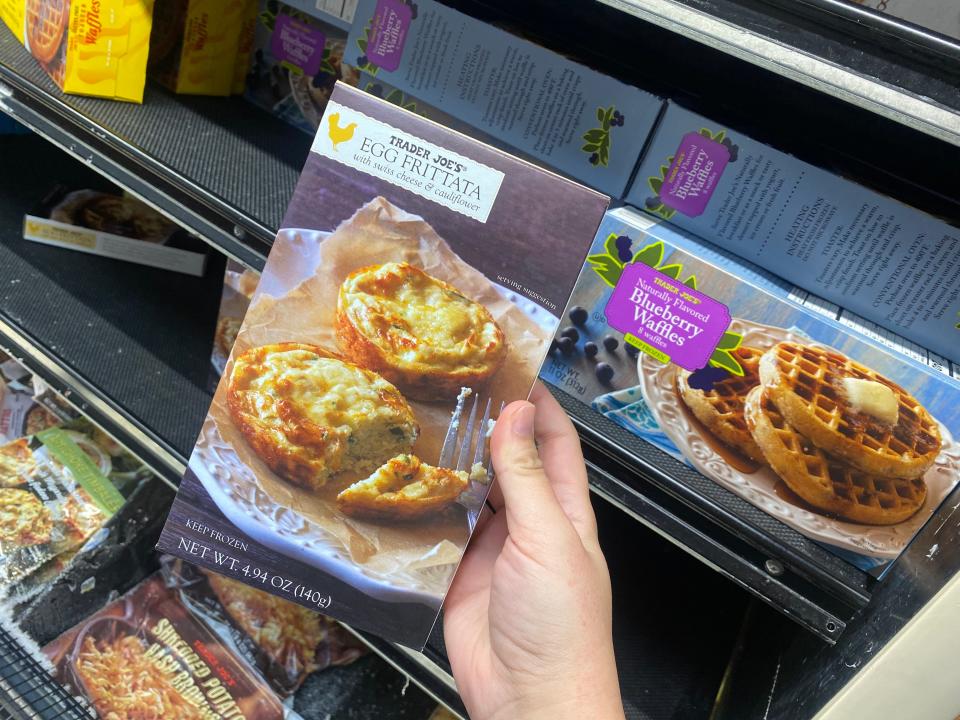 hand holding box of frozen egg frittatas at trader joes freezer aisle