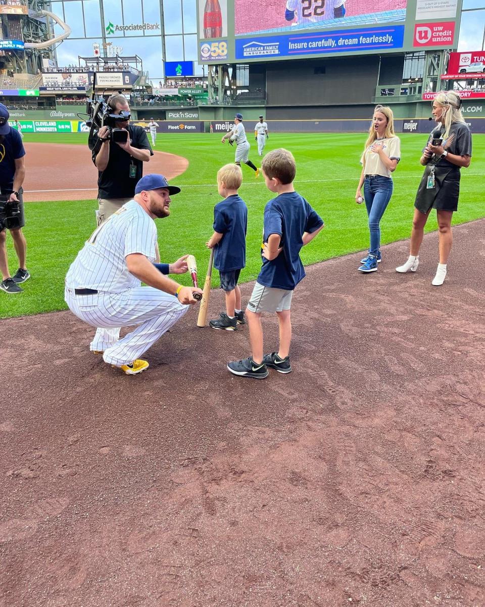 Brewers first baseman Rowdy Tellez presents signed bats to Miles Michaelis (left) and Clayton Michaelis before the Brewers game against the Reds on Sept. 10, 2022. The boys were on the field as part of Festival Foods' "Play Ball" promotion. Their mother, Elizabeth, died of cancer in April; Tellez's own mother, Lori, died after battling cancer in 2018.