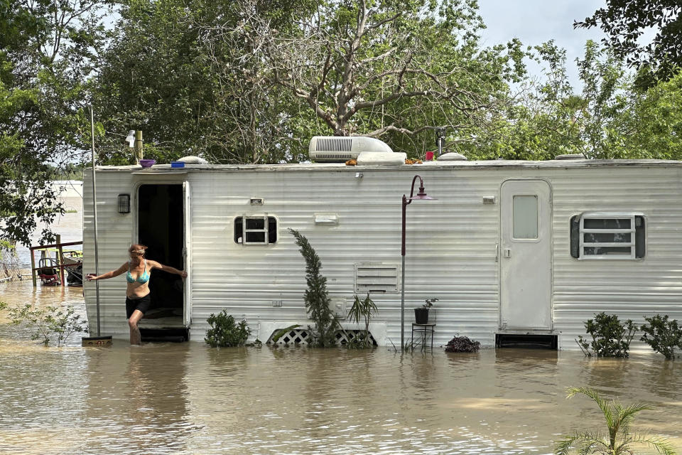 A woman steps out of a mobile home in an unincorporated area in east Harris County near Houston on Saturday afternoon, May 4, 2024. The mobile home was surrounded by flood waters caused by the nearby San Jacinto River, which was overflowing due to heavy rainfall earlier this week. (AP Photo/Juan Lozano)