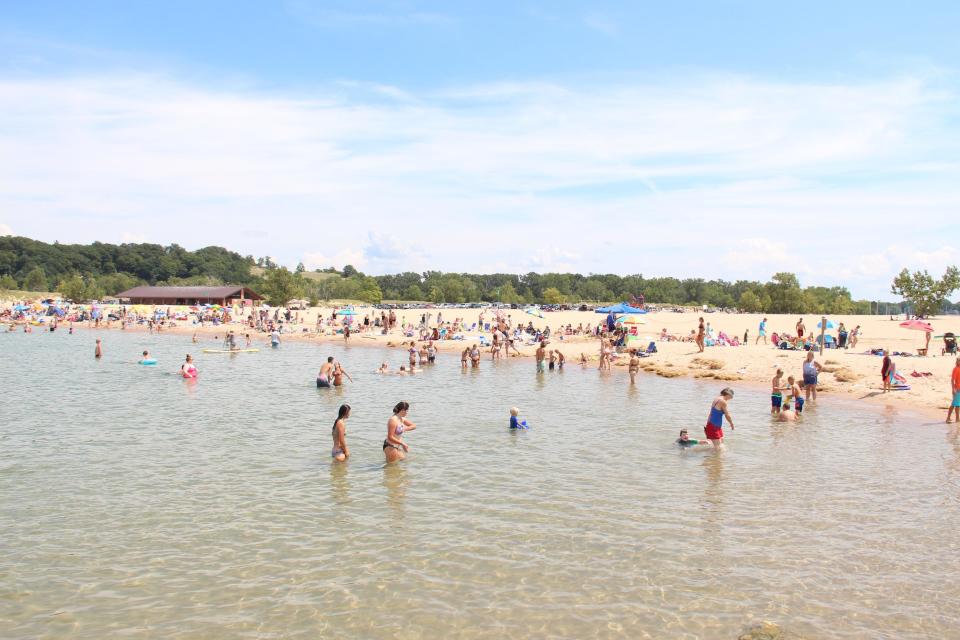People sit along and swim in Lake Michigan at Holland State Park in Holland. Local public safety officials are urging caution during all water-related activities.