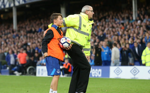 The young ball boy is protected by a steward following crowd violence - Credit:  Sportimage