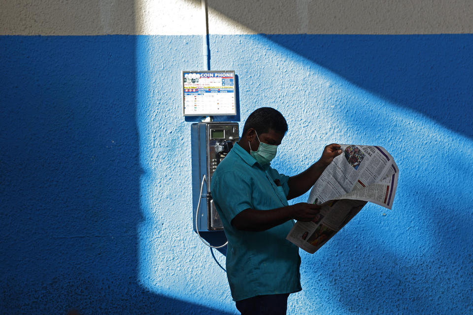 A man wearing a protective mask reads a newspaper on 4 April, 2020 in Singapore. (PHOTO: Getty Images)