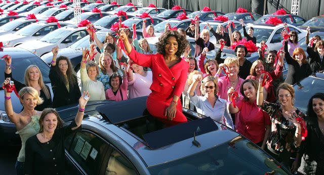 <p>AP Photo/Harpo Productions</p> Oprah Winfrey sitting atop a Pontiac G6 Sept. 9, 2004 after giving away cars to her audience