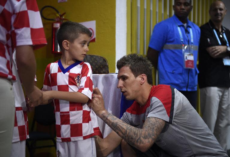 Croatia’s Mario Mandzukic (R) signs a fan's shirt after a training session in Praia do Forte, on June 9, 2014