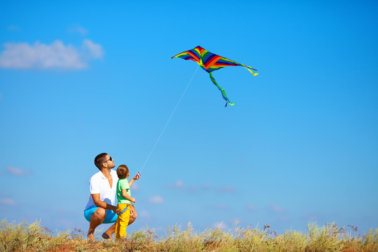 father and son having fun, playing with kite together