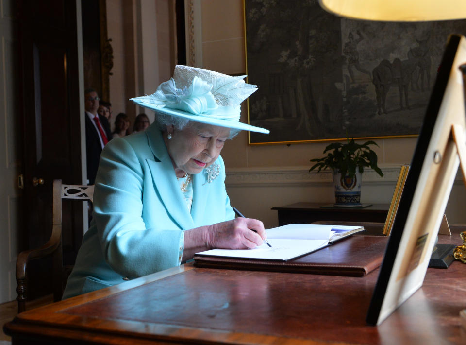 BELFAST, NORTHERN IRELAND - JUNE 25:  (EDITORIAL USE ONLY, NO SALES) In this handout image provided by Harrison Photography, Queen Elizabeth II signs the visitors book at Hillsborough castle as they leave for their final engagement in Coleraine on June 25, 2014 in Belfast, Northern Ireland. The Royal party are visiting Northern Ireland for three days.  (Photo byAaron McCracken/Harrison Photography via Getty Images)