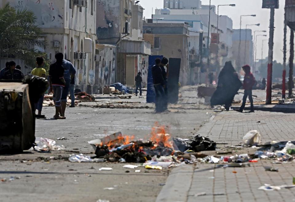 Bahraini anti-government protesters watch for riot police between clashes in the debris-filled main street of Malkiya, Bahrain, Thursday, Feb. 13, 2014. Rubbish and oil smeared on the road are meant to deter police jeeps from entering the village, where shops were shuttered in observance of a general strike called by anti-government groups in the run-up to Friday's third anniversary of the pro-democracy uprising in the Gulf island kingdom. (AP Photo/Hasan Jamali)