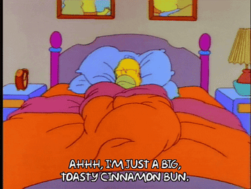 A GIF image of Homer Simpson in bed, saying "Ahh, I'm just a big, toasty cinnamon bun"