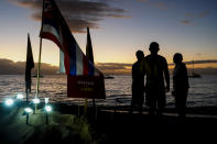 People stand by a "defend the land" sign, at a "Fishing for Housing" protest, Wednesday, Dec. 6, 2023, Kaanapali Beach in Lahaina, Hawaii. A group of survivors is camping on the resort beach to protest and raise awareness for better long-term housing options for those displaced. Residents and survivors still dealing with the aftermath of the August wildfires in Lahaina have mixed feelings as tourists begin to return to the west side of Maui, staying in hotels still housing some displaced residents. (AP Photo/Lindsey Wasson)