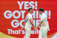 Australia's Pat Cummins, left, is congratulated by teammate Cameron Green after taking the wicket of England's Haseeb Hameedduring day one of the first Ashes cricket test at the Gabba in Brisbane, Australia, Wednesday, Dec. 8, 2021. (AP Photo/Tertius Pickard)