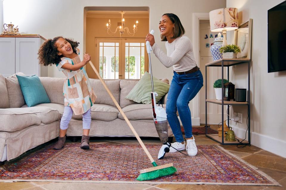 shot of a mother and daughter having fun while cleaning the living room