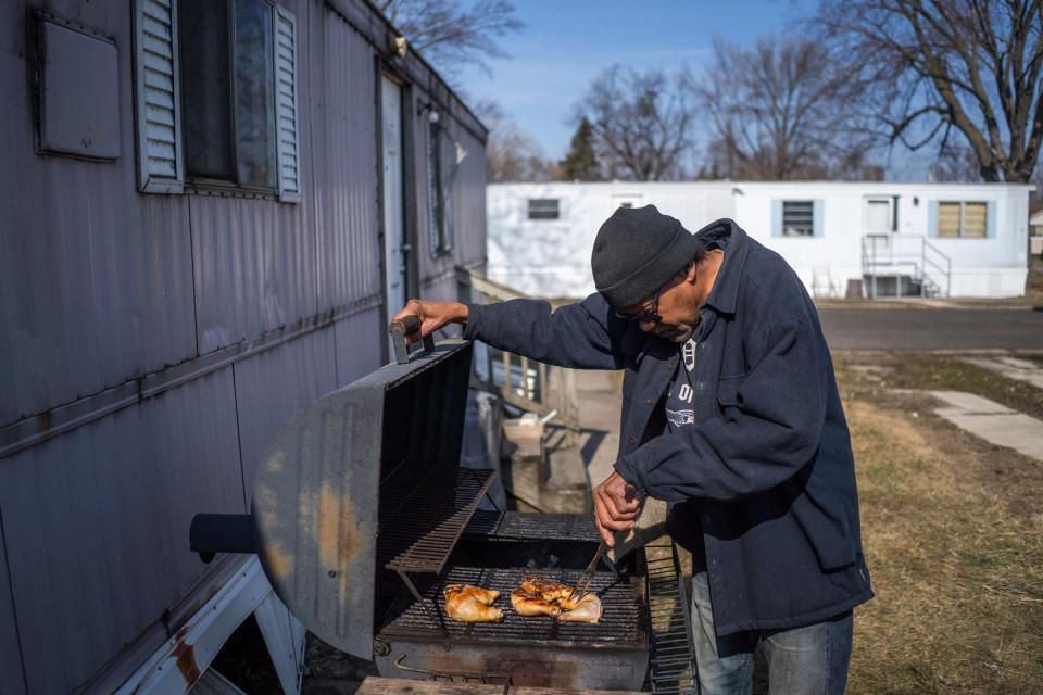 Landmark Estates resident Lloyd Johnson, 67, grills chicken outside of his trailer at his mobile home park in Warren on Monday, Feb. 26, 2024.