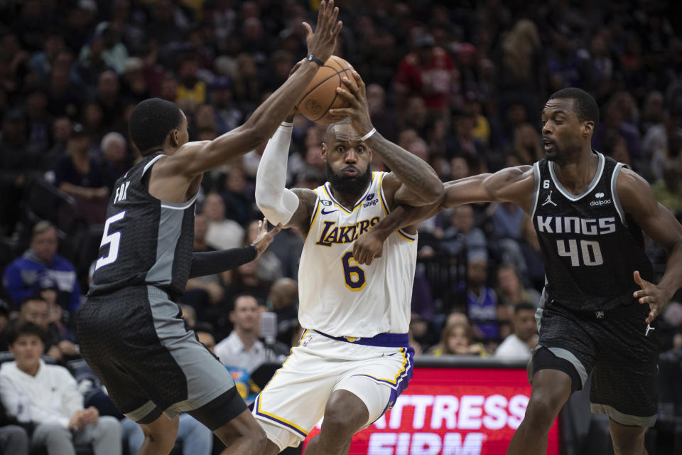 Sacramento Kings guard De'Aaron Fox (5) and forward Harrison Barnes (40) defend against Los Angeles Lakers forward LeBron James (6) during the second half of an NBA basketball game in Sacramento, Calif., Saturday, Jan. 7, 2023. The Lakers won 136-134. (AP Photo/José Luis Villegas)