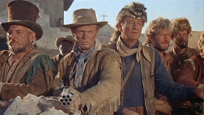John Wayne, center, wore a coonskin cap when playing Davy Crockett in "The Alamo," a 1960 Hollywood movie.
