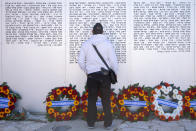 An Israeli man looks for s friend's name on a memorial wall during a ceremony marking the annual Memorial Day to remember fallen soldiers and victims of terror, at the Armored Corps memorial site in Latrun, Israel, Wednesday, April 14, 2021. (AP Photo/Oded Balilty)