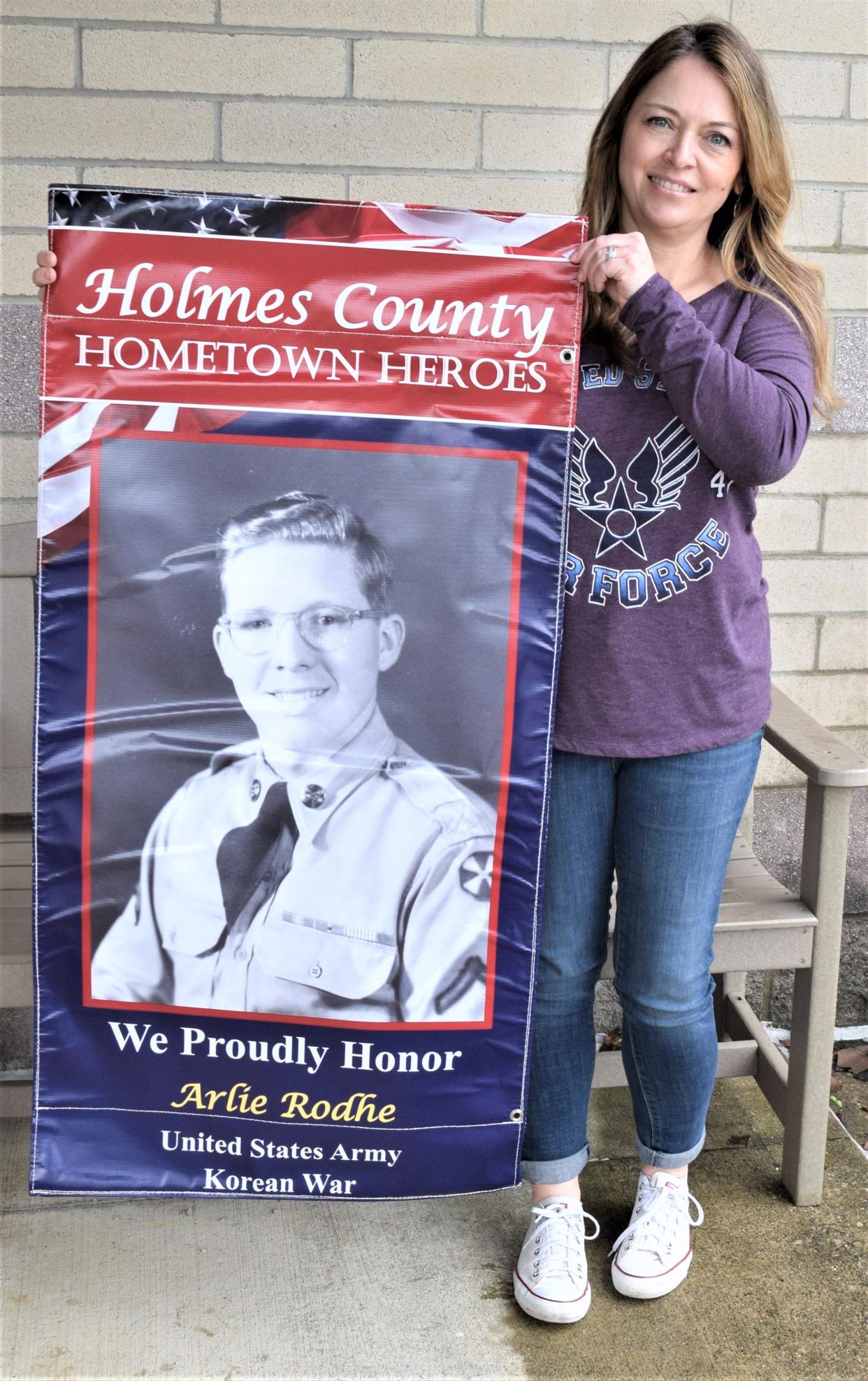 Millersburg Lions Club member Debbie Mullen displays one of the Hometown Heroes banners the Lions Club will be displaying on poles in the village of Millersburg from Memorial Day through the Fourth of July.