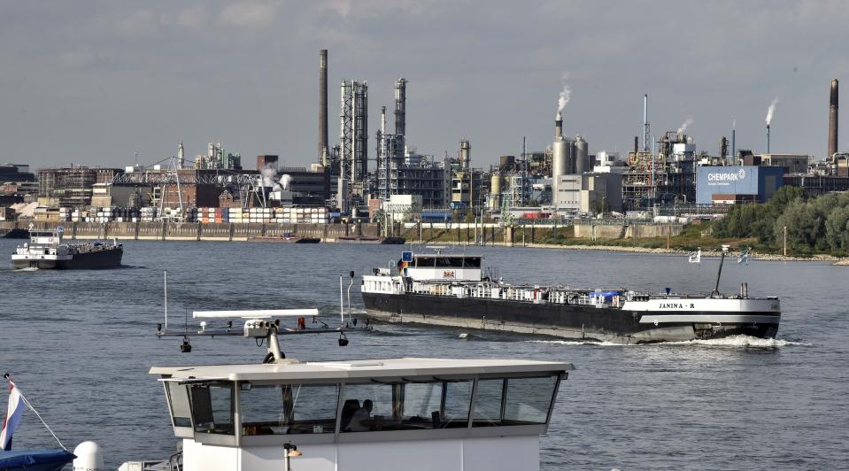 FILE - Ships pass the main chemical plant of German Bayer AG at the river Rhine on Thursday, Aug. 9, 2019 in Leverkusen, Germany. A low-rise city of 167,000 that grew up around the factories of the pharmaceuticals giant Bayer, Leverkusen has little to draw tourists besides its internationally famed soccer club. The team finished an entire German Bundesliga season unbeaten Saturday and is now targeting trophies in the Europa League and German Cup.(AP Photo/Martin Meissner, File)
