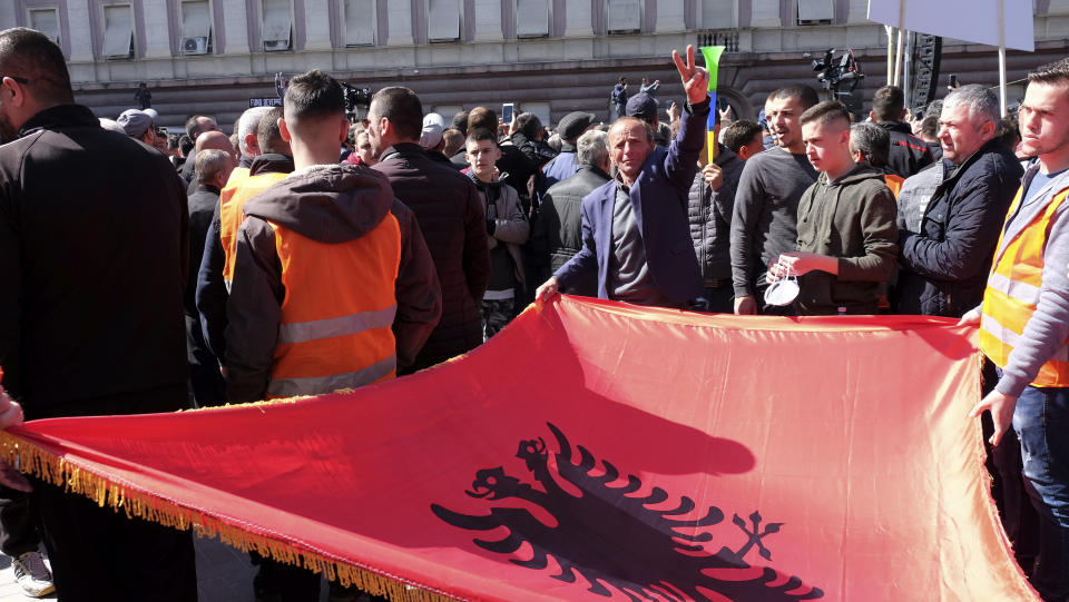Protesters hold an Albanian flag during an anti-government rally in Tirana, Albania, Saturday, March 16, 2019. Thousands of supporters of the center-right Democratic Party-led opposition have gathered on Saturday in front of Socialist Party's Prime Minister Edi Rama to demand his resignation, a transitory Cabinet without him that will prepare fresh elections. (AP Photo/ Hektor Pustina)