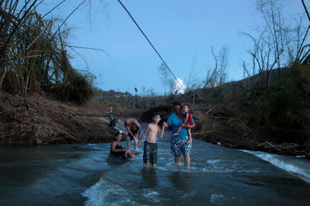 Local residents walk in a river after Hurricane Maria destroyed the town's bridge in San Lorenzo, Morovis, Puerto Rico, October 4, 2017. REUTERS/Alvin Baez