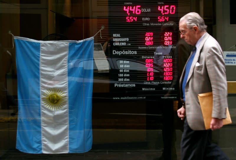 Foto de archivo: un hombre camina frente a un cartel con la cotización de monedas en Buenos Aires