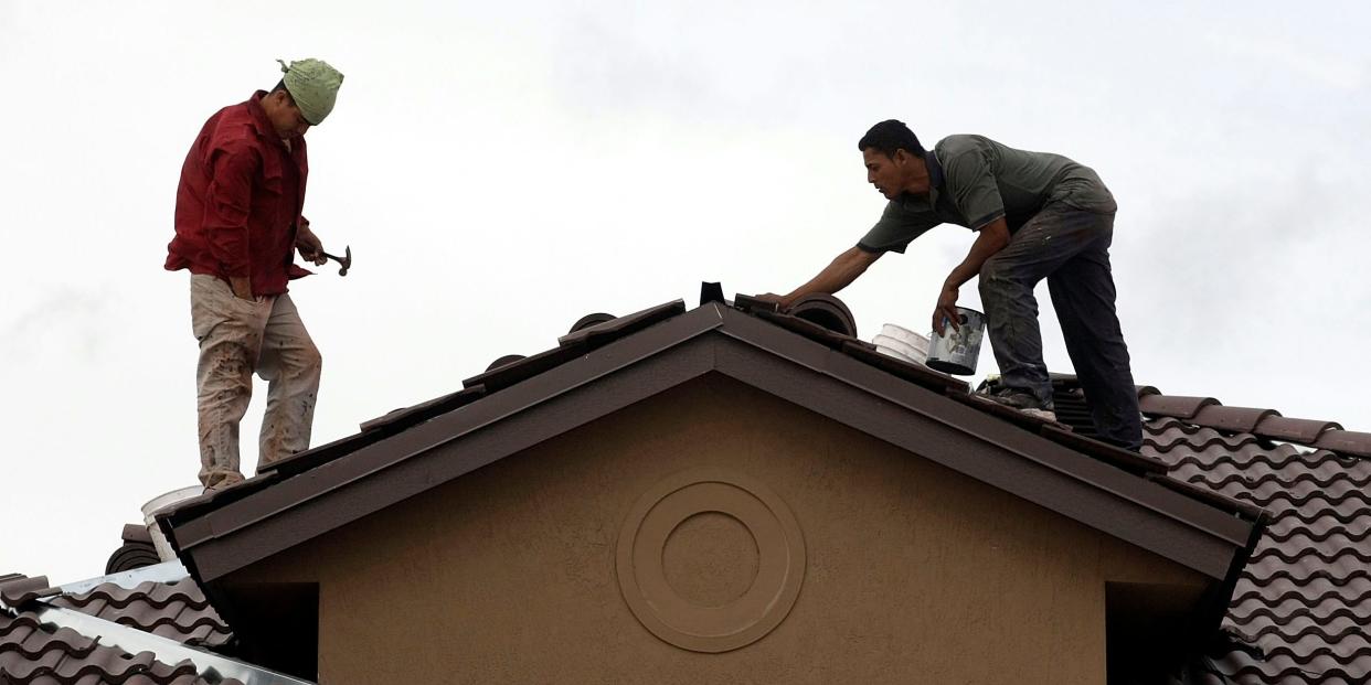 men building a house standing on roof