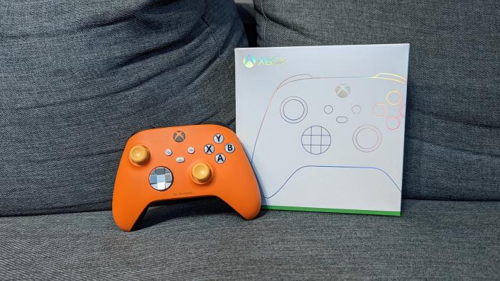 An orange Xbox controller with its white packaging on a grey coloured cushion. (Photo: Yahoo Gaming SEA)