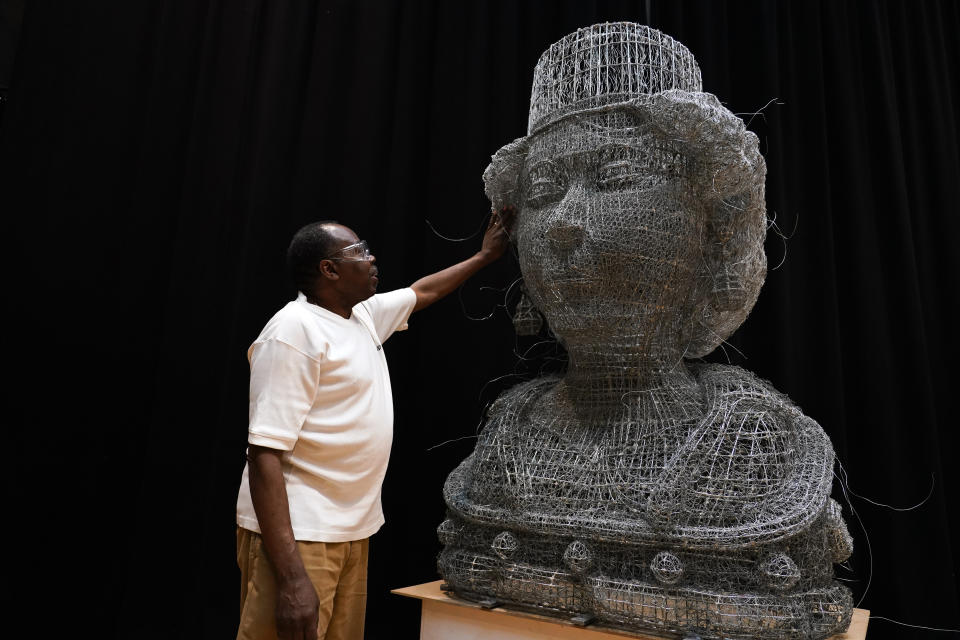 Artist Carl Gabriel touches his sculpture made of wire depicting the head of Britain's Queen Elizabeth II, made for the Jubilee Pageant, ahead of the Platinum Jubilee weekend, in London, June 1, 2022. (AP Photo/Alberto Pezzali)