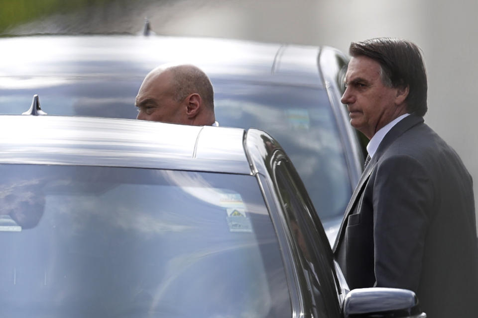 Photographed through a fence, Brazilian President Jair Bolsonaro gets into a car after talking to supporters as he leaves the presidential residence, Alvorada Palace, in Brasilia, Brazil, Friday, March 19, 2021. (AP Photo/Eraldo Peres)